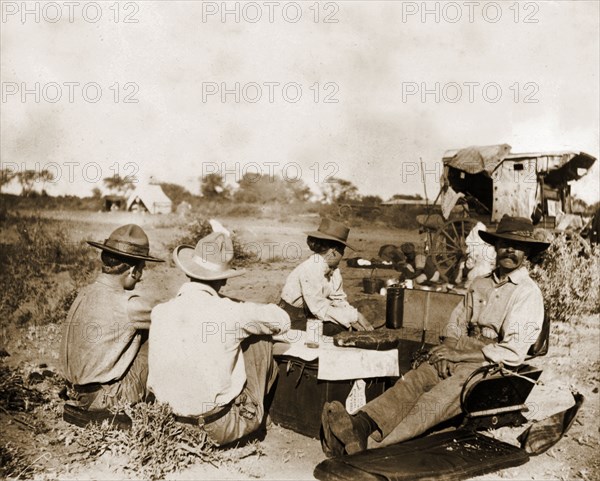 Captain Lawley relaxes in camp. Captain Arthur Lawley (1860-1932) (front right) rests with fellow European travellers during an overland journey from South Africa to Rhodesia. Accompanied by Earl Grey (1851-1917), he was travelling with relief forces and supplies to Bulawayo, which had been besieged during the Matabele rebellion. Probably Matabeleland, Rhodesia (Matabeleland South, Zimbabwe), circa March 1896., Matabeleland South, Zimbabwe, Southern Africa, Africa.