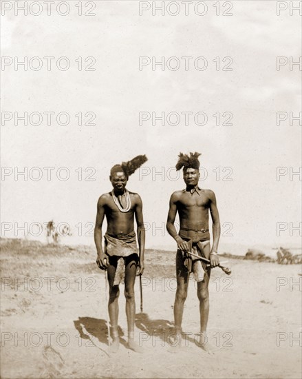 Portrait of two Matabele indunas. Portrait of two Matabele (Ndebele) indunas (chiefs), semi-naked and wearing feathered headdresses at an indaba (council) with Cecil Rhodes. Rhodes and his comrades travelled unarmed into the Matapos Hills for three such indabas and successfully negotiated an end to the Matabele rebellion. Near Bulawayo, Rhodesia (Zimbabwe), circa August 1896., Matabeleland North, Zimbabwe, Southern Africa, Africa.