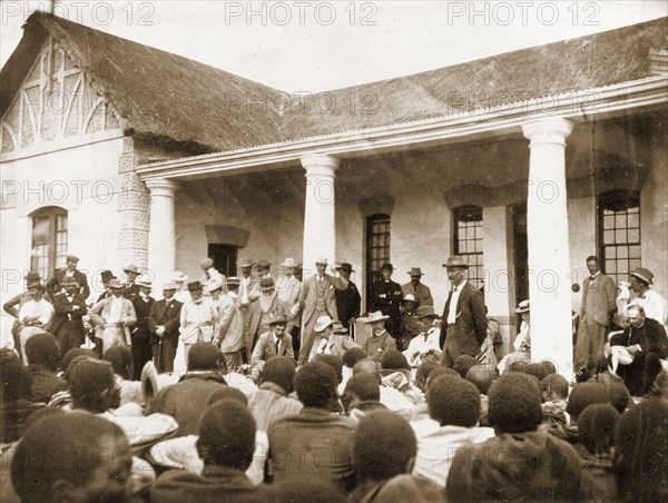 An indaba at Government house. A group of British administrators stand before a seated audience of Matabele (Ndebele) indunas (chiefs) at an indaba (council) held at Government House. Bulawayo, Rhodesia (Zimbabwe), November 1897. Bulawayo, Zimbabwe, Southern Africa, Africa.