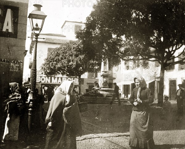 A town square in Madeira. Tramlines run through a busy town square in Funchal, which is flanked by shops with a stone monument at its centre. Funchal, Madeira, circa 1897. Funchal, Madeira, Madeira Islands (Portugal), Atlantic Ocean, Africa.