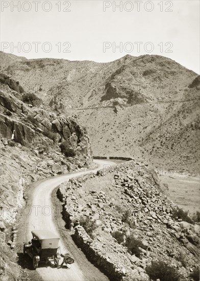 Near the site of Mollie Ellis' abduction. A motorcar pauses on a winding mountain road near the site where Mollie Ellis, the daughter of a British Army Commander, was held captive by a band of Afridi rebels during an incident that shocked the European colonial community. North West Frontier Province, India (Pakistan), circa 1928., North West Frontier Province, Pakistan, Southern Asia, Asia.