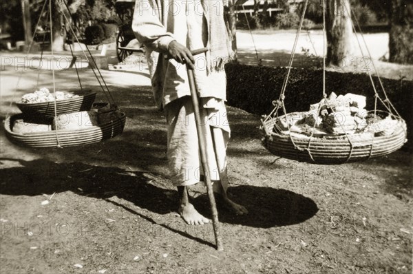 Sweetmeat vendor. A sweetmeat vendor wanders the streets looking for custom, carrying his goods in two baskets suspended from a pole across his shoulders. North West Frontier Province, India (Pakistan), circa 1927., North West Frontier Province, Pakistan, Southern Asia, Asia.