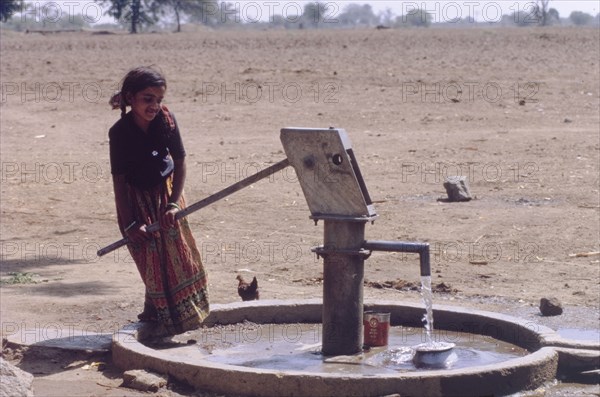 Raising water from a borewell. A young girl operates a hand pump to raise water from a borewell. Andhra Pradesh, India, circa 1985., Andhra Pradesh, India, Southern Asia, Asia.
