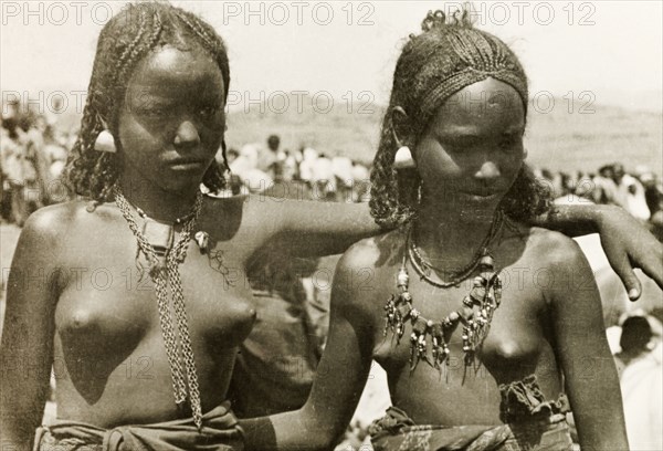 Two young Eritrean women. Portrait of two young Eritrean women, taken at an outdoor camel market. Naked from the waist up, their hair is braided and they wear decorative necklaces and earrings. Eritrea, 1943. Eritrea, Eastern Africa, Africa.