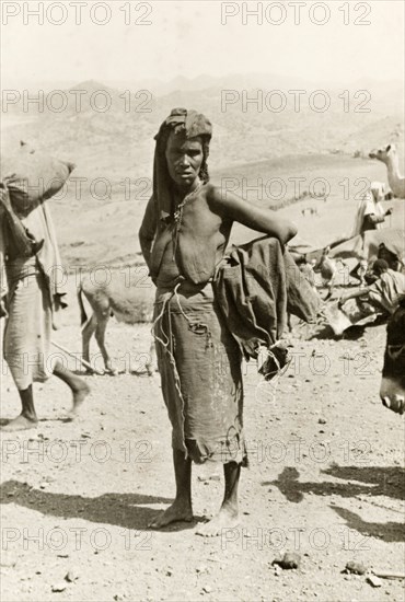 Portrait of an Eritrean woman. Portrait of a middle-aged Eritrean woman at an outdoor camel market. Naked from the waist up, she stands barefoot with her hands on her hips, an empty sack slung over one arm. Eritrea, 1943. Eritrea, Eastern Africa, Africa.