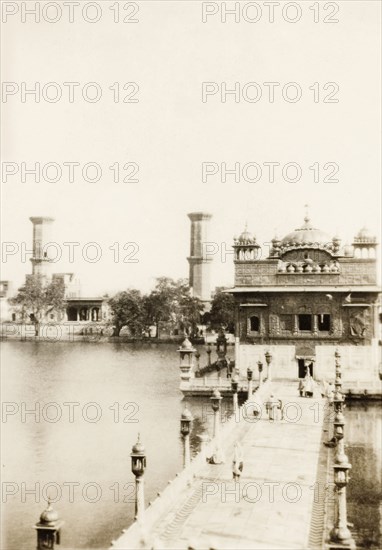 The Harimandir Sahib at Amritsar. A walkway leads over a pool to the Harimandir Sahib, or Golden Temple, the most sacred gurdwara (Sikh temple) in all of Sikhism. Amritsar, Punjab, India, circa 1920. Amritsar, Punjab, India, Southern Asia, Asia.