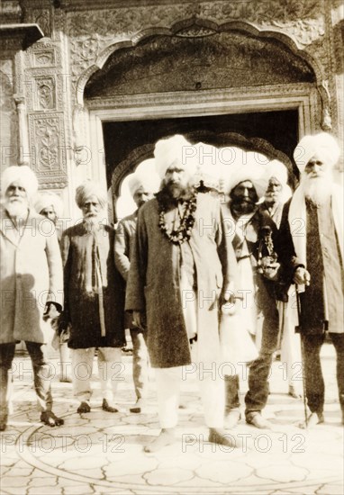 Sikh men at the Harimandir Sahib. A group of turbaned Sikh men stand in front of an ornate archway at the entrance to the Harimandir Sahib, or Golden Temple, the most sacred gurdwara (Sikh temple) in all of Sikhism. Amritsar, Punjab, India, 26 February 1920. Amritsar, Punjab, India, Southern Asia, Asia.