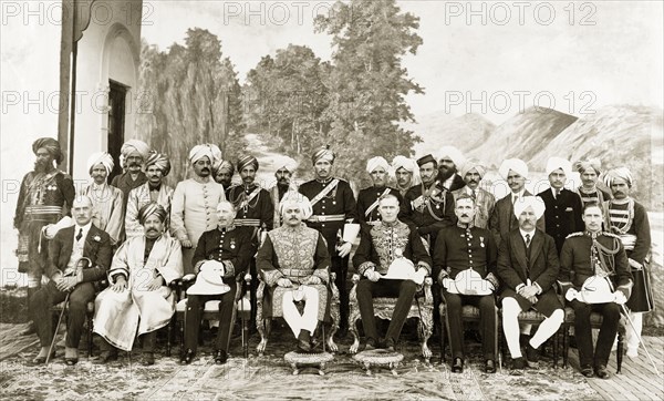 Sir Edward Maclagan and the Raja of Suket. Sir Edward Maclagan, Lieutenant Governor of the Punjab, and the Raja of Suket pose for a group portrait against a painted backdrop with British government officials and Indian dignitaries. Probably Suket, Rajputana (Rajasthan), India, 1920. Suket, Rajasthan, India, Southern Asia, Asia.