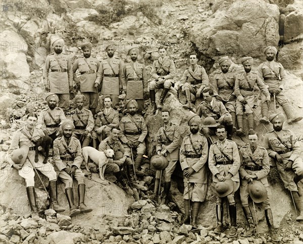 14th Sikh Regiment of the Indian Army. The 14th Sikh Regiment pose for a group portrait on a rocky mountainside, dressed in full military uniform and equipped with hiking sticks. Probably Punjab, India (Pakistan), circa 1920., Punjab, Pakistan, Southern Asia, Asia.