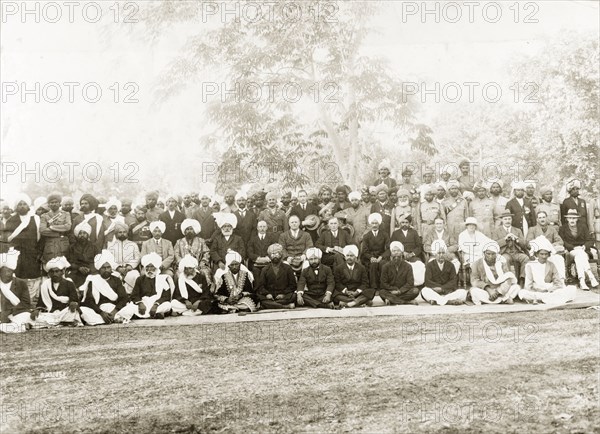 A garden party at Mianwali. Group portrait of a number of Indian officials, accompanied by eight European guests at a garden party. Related images suggest some of the men may be part of the 14th Sikh Regiment of the Indian Army. Mianwali, Punjab, India (Pakistan), 1920. Mianwali, Punjab, Pakistan, Southern Asia, Asia.
