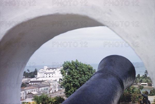 Elmina Castle from Fort St Jago. Distant view of Elmina Castle, taken through a cannon hole at Fort St Jago. Elmina, Ghana, circa 1959. Elmina, Central (Ghana), Ghana, Western Africa, Africa.
