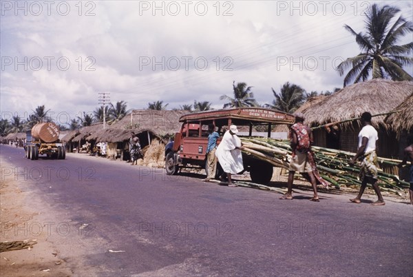 Unloading bamboo near Cape Coast'. Men unload bamboo from an open-sided truck at a roadside near Cape Coast. Cape Coast, Ghana, circa 1958. Cape Coast, Central (Ghana), Ghana, Western Africa, Africa.