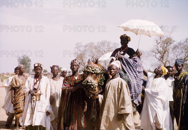 Fourth anniversary of Ghanaian independence. A Dagomba sub-chief or elder rides on a caparisoned horse beneath an umbrella during celebrations for the fourth anniversary of Ghanaian independence. Savelugu, Ghana, circa March 1961. Savelugu, North (Ghana), Ghana, Western Africa, Africa.