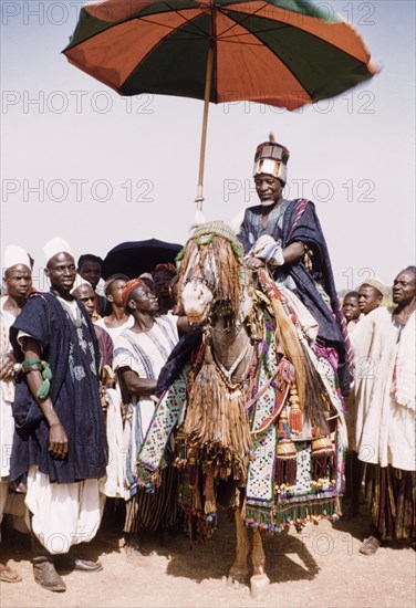 Fourth anniversary of Ghanaian independence. A Dagomba sub-chief or elder rides on a caparisoned horse beneath an umbrella during celebrations for the fourth anniversary of Ghanaian independence. Savelugu, Ghana, circa March 1961. Savelugu, North (Ghana), Ghana, Western Africa, Africa.