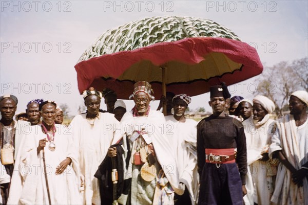 Visit of Ya Na Abdulai III. The King of Dagbon, Ya Na Abdulai III (r.1953-67), attends a celebration for the fourth anniversary of Ghanaian independence. He is dressed in a batakari (smock) and wears a hat studded with amulets for spiritual protection. Savelugu, Ghana, circa March 1961. Savelugu, North (Ghana), Ghana, Western Africa, Africa.