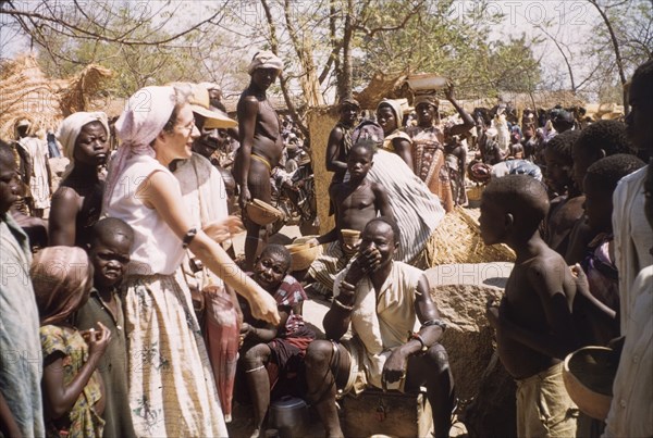 Joyce strikes a bargain. A British woman identified as 'Joyce', bargains with traders at a busy street market in Bolgatanga. Bolgatanga, Ghana, circa 1961. Bolgatanga, Upper East, Ghana, Western Africa, Africa.