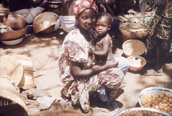 Mother and baby at a vegetable stall, Ghana. A mother and her baby daughter are pictured on a vegetable stall at Bawku market. Bawku, Ghana, circa March 1961. Bawku, Upper East, Ghana, Western Africa, Africa.