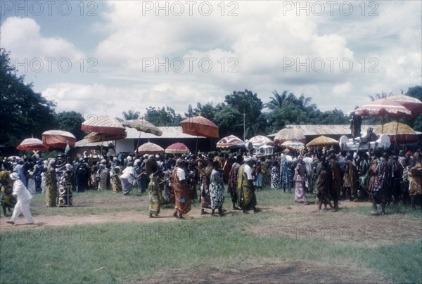 Crowds at a Ngmayem festival. Crowds of people celebrate an annual Ngmayem harvest festival at Odumasi. Several Manya Krobo chiefs are ferried along in palanquins shaded by ceremonial umbrellas. Odumasi, Ghana, circa 1960. Odumasi, East (Ghana), Ghana, Western Africa, Africa.