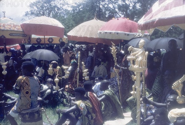 Linguists' staffs at the Ngmayem festival. Several 'okyeames' (linguists) sit beneath ceremonial umbrellas with their 'pomas' (linguists' staffs) at an annual Ngmayem harvest festival. The linguists were acting as ambassadors to a number of Manya Krobo chiefs who attended this event. Odumasi, Ghana, circa 1960. Odumasi, East (Ghana), Ghana, Western Africa, Africa.