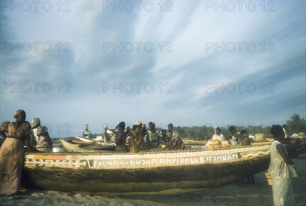 Waiting on the beach at Saltpond. Several women wait beside painted fishing boats lying on a beach in Saltpond. Saltpond, Ghana, circa 1960. Saltpond, West (Ghana), Ghana, Western Africa, Africa.