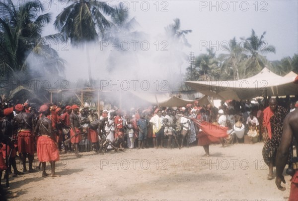 Asafo company firing guns. Members of Asafo Number Two Company swing flags and fire guns at a ceremony in Lowtown. Saltpond, Ghana, April 1960. Saltpond, West (Ghana), Ghana, Western Africa, Africa.