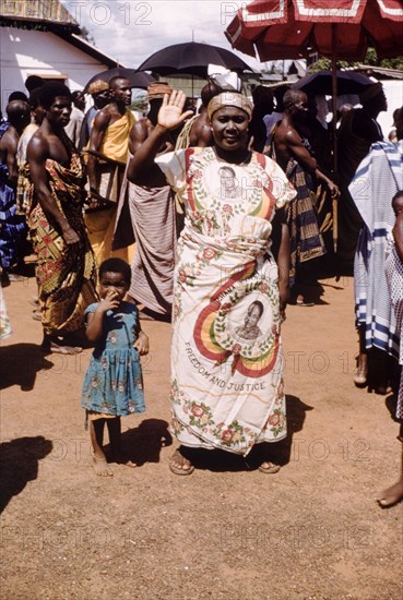 Independence cloth. A smiling woman wears a wrap-around cloth printed with the image of the Ghanaian politican Kwama Nkrumah (1909-1972), during celebrations to mark Ghana becoming a Republic under the Nkrumah's presidency. Saltpond, Ghana, circa 1960. Ghana, Western Africa, Africa.