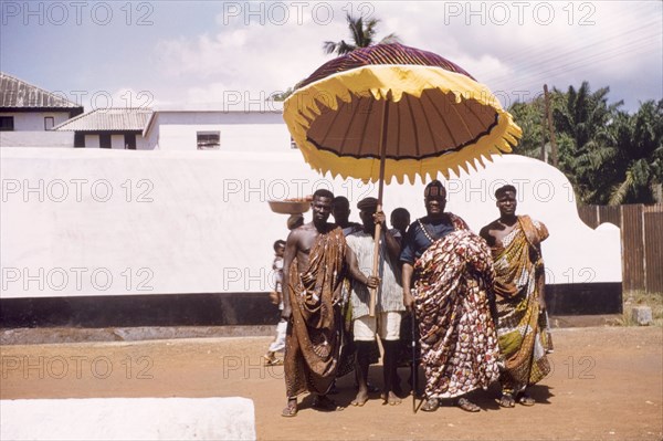 Ghanaian chief with his retinue. A Ghanaian chief poses with his retinue beneath a ceremonial umbrella. Saltpond, Ghana, circa 1960. Saltpond, West (Ghana), Ghana, Western Africa, Africa.