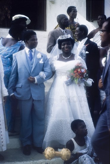 A newlywed Ghanaian couple. A newlywed Ghanaian couple, Ben and Victoria, socialise with their friends and family on the steps of a church. Ghana, 23 April 1960. Ghana, Western Africa, Africa.