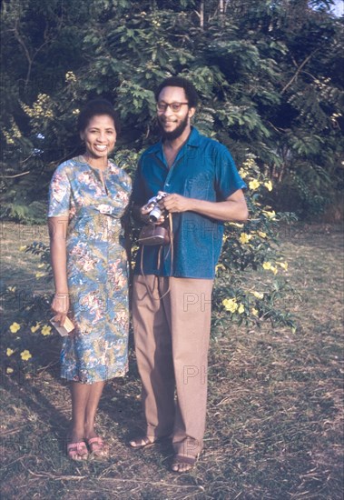 Edward and Doris Brathwaite. Portrait of Ghanaian couple identified as Edward and Doris Brathwaite. They stand in a garden posing for the camera: Doris wearing a floral dress and sandals, Edward holding a camera. Ghana, circa 1960. Ghana, Western Africa, Africa.