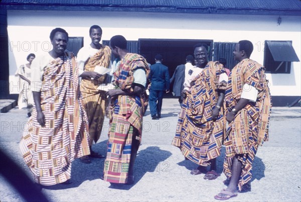 Ghanaian men wearing kente cloth. A group of Ghanaian men wear traditional kente cloth at a farewell party for Wilma Gladstone, a British Principal Education Officer who retired to Scotland after a long career in the Gold Coast education service. Saltpond, Ghana, July 1961. Saltpond, West (Ghana), Ghana, Western Africa, Africa.