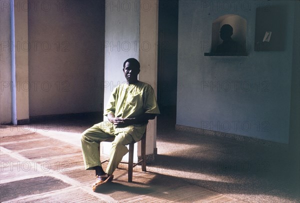Portrait of a domestic servant. Portrait of a domestic servant, seated in the light of a doorway in a bare room. Sierra Leone, circa 1960. Freetown, West (Sierra Leone), Sierra Leone, Western Africa, Africa.
