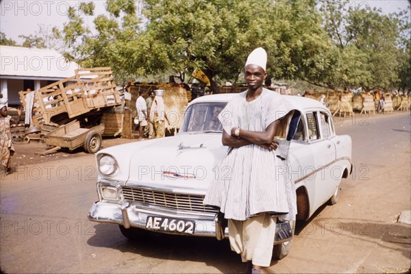 Mumuni Bawumia, Paramount Chief of Kperiga. Mumuni Bawumia (c.1927-2002), Paramount Chief of Kperiga, poses by his car on a street in Tamale. Tamale, Ghana, circa 1961. Tamale, North (Ghana), Ghana, Western Africa, Africa.