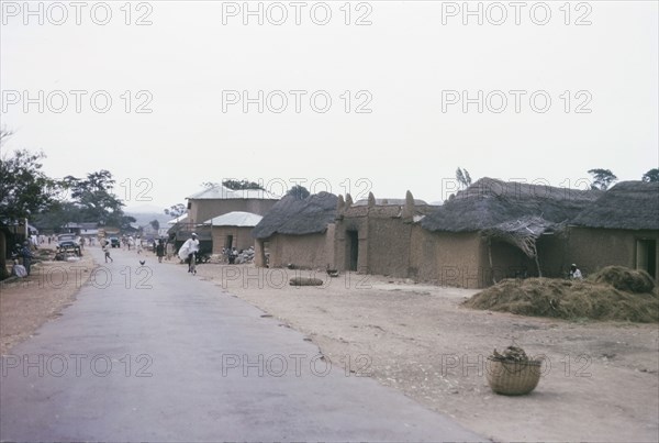 Main road through a Hausa village. Low, mud-walled buildings flank the main road running through a Hausa village. Nigeria, October 1963. Nigeria, Western Africa, Africa.