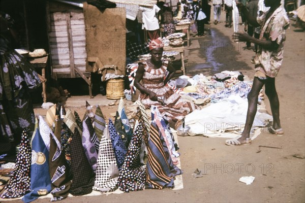 Cloth at a street market in Freetown. A female street trader sells rolls of patterned cloth on a market stall in Freetown. Freetown, Sierra Leone, 15 February 1964. Freetown, West (Sierra Leone), Sierra Leone, Western Africa, Africa.