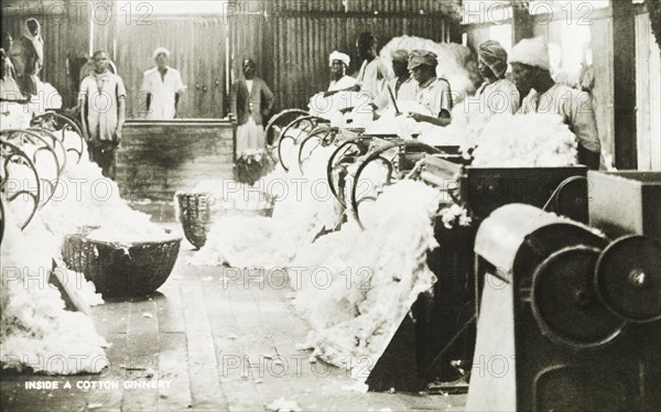 Inside a cotton ginnery. Workers in a cotton factory operate roller gins to separate the cotton fibres from the seeds. Nigeria, circa 1920. Nigeria, Western Africa, Africa.