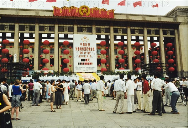 Celebrating the handover of Hong Kong. A crowd of people gather in a piazza outside a building adorned with lantern and flag decorations, during celebrations to mark the transfer of Hong Kong's sovereignty from the United Kingdom to the People's Republic of China. Beijing, China, 1 July 1997. Beijing, Beijing, China, People's Republic of, Eastern Asia, Asia.