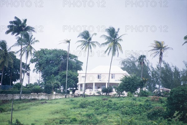 Plantation house in Barbados. View of a colonial plantation house in Barbados, situated amongst palm trees and vegetation. Barbados, circa 1975. Barbados, Caribbean, North America .