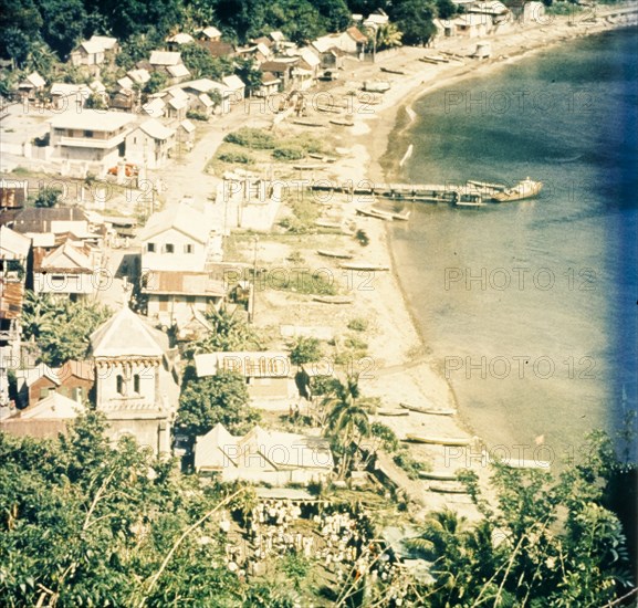 Coastal settlement in Dominica. View across a coastal settlement and beach bordering the Caribbean Sea. Dominica, circa 1975. Dominica, Caribbean, North America .