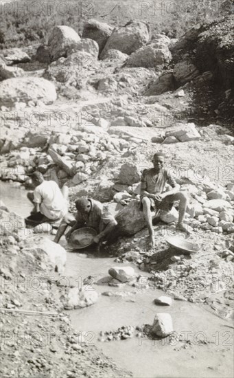 Panning for gold at Kakamega. African labourers pan for gold in the dried-up Wacheche River, located in the Kakamega goldfields. An original caption comments: "About an ounce a day, mainly in small nuggets, is extracted from this claim". Kakamega, Kenya, 1933. Kakamega, West (Kenya), Kenya, Eastern Africa, Africa.