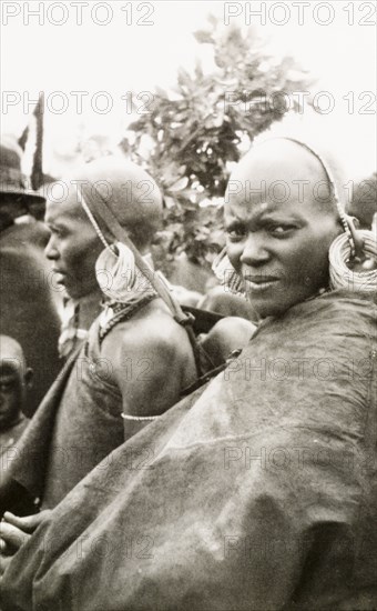 Portrait of two Kenyan women. Profile of two African women, one of whom carries a baby in a sling on her back. They wear wraparound robes and masses of hoop earrings looped through a beaded headband. Rift Valley, Kenya, circa 1933., Rift Valley, Kenya, Eastern Africa, Africa.