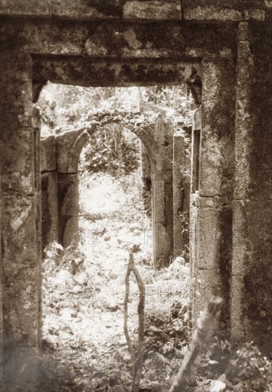 Doorway at the ruins of Gedi. View of a stone arch and doorway amidst the ruins of Gedi, an ancient Muslim town that was abandoned in the 17th century. The settlement featured a mosque, a palace and several large stone houses, and is thought to have been populated by around 2,500 people. Gedi (Gede), Coastal Region, Kenya, 1933. Gede, Coast, Kenya, Eastern Africa, Africa.