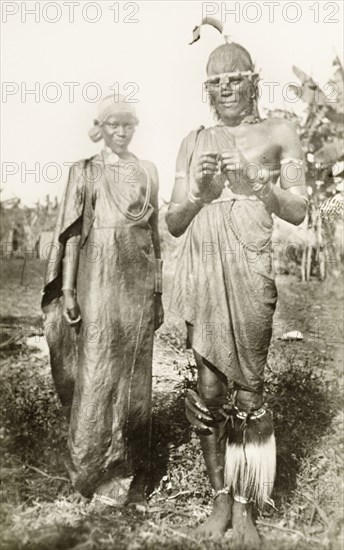 Two Kikuyu dancers. Full-length portrait of two Kikuyu dancers wearing traditional dress and headgear. British East Africa (Kenya), circa 1912. Kenya, Eastern Africa, Africa.
