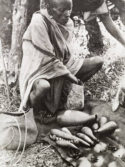 Reading the beans'. A witch doctor prepares to tell the fortune of a client, using beans contained in a number of small stoppered gourds. South Nyeri, Kenya, 1936. Nyeri, Central (Kenya), Kenya, Eastern Africa, Africa.