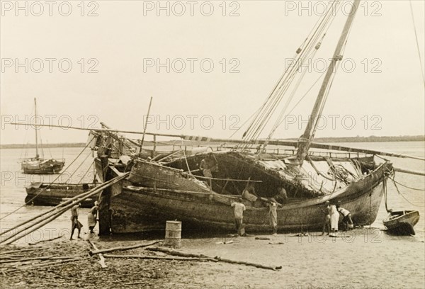 Repairing a dhow at Lamu, Kenya. Men repair a dhow, which is dry-docked on a beach at Lamu. Lamu, Kenya, 1947. Lamu, Coast, Kenya, Eastern Africa, Africa.