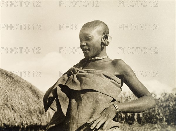 A married Kikuyu woman. Portrait of a married Kikuyu woman, dressed in a wrap-around cloth tied at the shoulder with jewellery including hooped earrings, a beaded necklace and a bracelet. Nyeri, Kenya, 1936. Nyeri, Central (Kenya), Kenya, Eastern Africa, Africa.