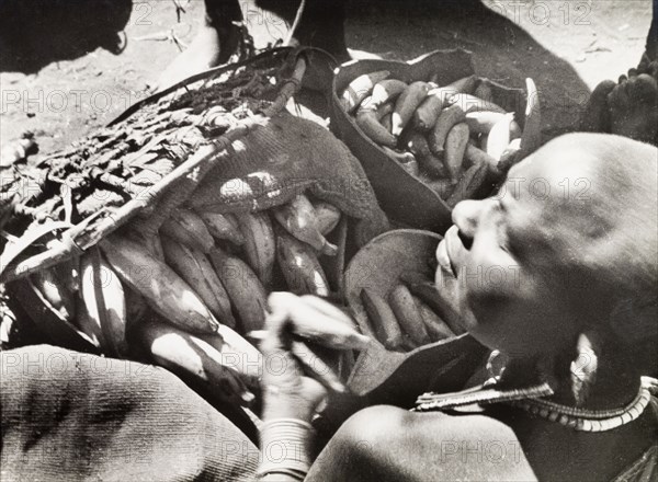 Banana seller at Karatune market. A Kikuyu trader sells bananas or plantains on a stall at Karatune market. South Nyeri, Kenya, 1936. Nyeri, Central (Kenya), Kenya, Eastern Africa, Africa.