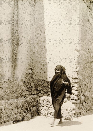 Woman in traditional Muslim dress. A woman wearing a traditional Muslim burqa walks along a street in Lamu. Lamu, Kenya, 1947. Lamu, Coast, Kenya, Eastern Africa, Africa.