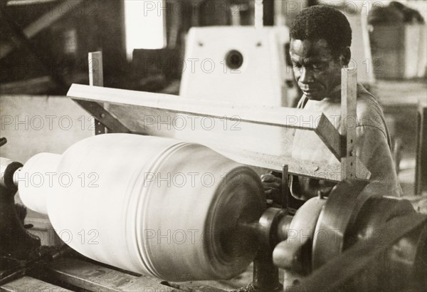 Craftsman operating a lathe, Ghana. A craftsman operates a wood-turning lathe to decorate the shell of an atumpan drum. Ghana, circa 1965. Ghana, Western Africa, Africa.