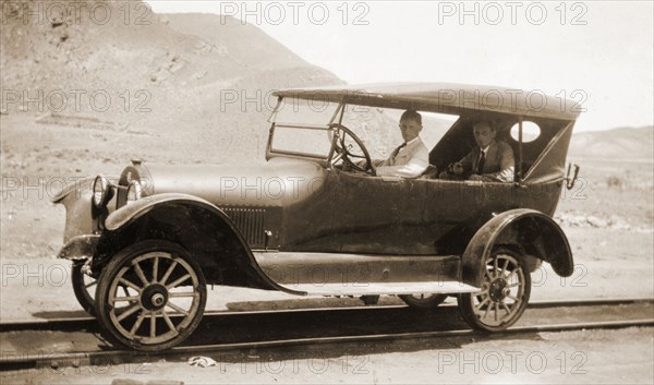 A car modified for rail, Peru. Jack Cooper drives a motor car that has been modified to travel on rails. A fellow European passenger sits in the backseat. Lima, Peru, circa 1920. Lima, Lima Metropolitana, Peru, South America, South America .