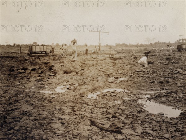 Extracting asphalt from the Pitch Lake. Labourers load lumps of asphalt extracted from Trinidad's Pitch Lake onto a waiting rail car. La Brea, Trinidad, circa 1910. Trinidad and Tobago, Caribbean, North America .